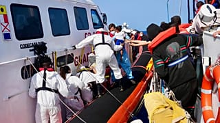 In this photo provided by RESQSHIP, Italian Coast Guard personnel evacuate migrants from the vessel NADIR off the coast of Lampedusa, Saturday 23 August 2025.