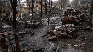 A woman walks amid destroyed Russian tanks in Bucha on the outskirts of Kyiv, 3 April, 2022