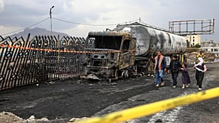 أشخاص يسيرون بجوار حطام شاحنة وقود دمرت في غارات جوية إسرائيلية يوم الأحد، في صنعاء، اليمن، الاثنين 25 أغسطس 2025. 