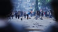 Manifestanti lanciano sassi verso la polizia antisommossa durante una protesta contro le laute indennità concesse ai membri del parlamento a Giacarta, 25 agosto 2025