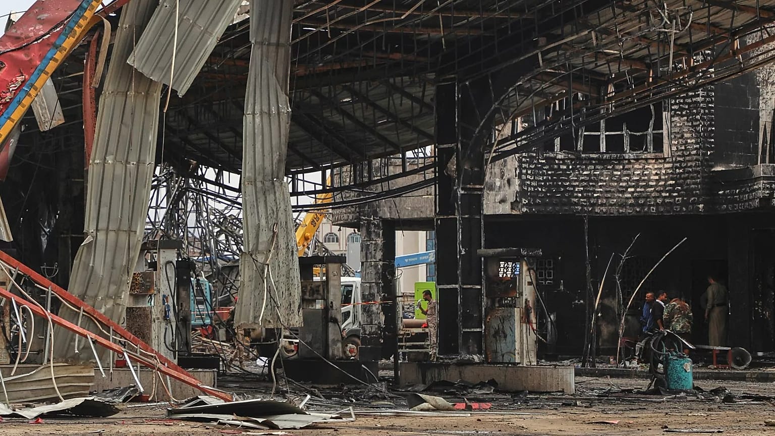 Des personnes inspectent une station-service endommagée par des frappes aériennes israéliennes à Sanaa, le 25 août 2025.