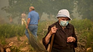 Lakosok sétálnak, miközben egy erdőtűz közeledik Rebordondo falu felé Spanyolországban, 2025. augusztus 18-án