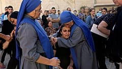 راهبات يواسين فلسطينية خلال جنازة أقاربها الذين قُتلوا في غارة إسرائيلية استهدفت كنيسة أرثوذكسية يونانية في غزة، 20 أكتوبر/تشرين الأول 2023
