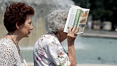 Una anciana se cubre la cara del sol abrasador con un periódico, en Milán, Italia, el jueves 25 de julio de 2019.