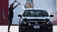 Un ciudadano limpiando su coche en medio de una ola de calor