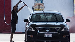 Un ciudadano limpiando su coche en medio de una ola de calor