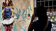 Μια γυναίκα φωτογραφίζει τον πίνακα "Άγγελος", που φιλοτέχνησε ο καλλιτέχνης δρόμου Harry Grebe νωρίτερα φέτος, αφιερωμένο στους δημοσιογράφους που σκοτώθηκαν στη Γάζα, στη Ρώμη, Δευτέρα, 25 Αυγούστου 2025.