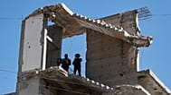 Varios agentes de seguridad sirios montan guardia en un edificio dañado por la guerra en Zamalka a las afueras de Damasco, Siria, el jueves 21 de agosto de 2025.