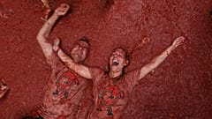 Ein Paar reagiert, als Feiernde sich gegenseitig mit Tomaten bewerfen während des jährlichen „Tomatina“-Tomatenschlachtfestes im Dorf Bunol bei Valencia, Spanien, am Mittwoch, den siebenundzwanzigsten August zweitausendfünfundzwanzig.