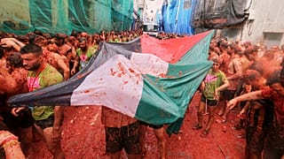 المحتفلون يحملون العلم الفلسطيني وهم يرمون الطماطم على بعضهم البعض خلال مهرجان قتال الطماطم السنوي "الطماطم", في قرية بونول بالقرب من فالنسيا, الأربعاء, أغسطس. 27, 2025