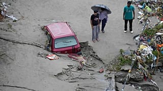 Hindistan’ın Cammu kentinde Tavi Nehri kıyısında meydana gelen ani selin ardından insanlar, mahsur kalan bir aracın yanında beklerken, 27 Ağustos 2025