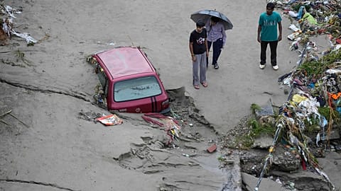 Hindistan’ın Cammu kentinde Tavi Nehri kıyısında meydana gelen ani selin ardından insanlar, mahsur kalan bir aracın yanında beklerken, 27 Ağustos 2025