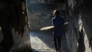 فلسطيني نازح ينزل درجًا حاملاً حلويات للبيع في مدرسة تابعة للأونروا تُستخدم كمأوى في مدينة غزة، الأربعاء، 27 آب/أغسطس 2025. 