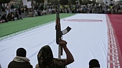 هواداران حوثی در جریان یک راهپیمایی هفتگی ضد آمریکایی و ضد اسرائیلی در صنعا، یمن، جمعه، ۲۰ ژوئن ۲۰۲۵ یک پرچم بزرگ از ایران را احاطه کرده‌اند.