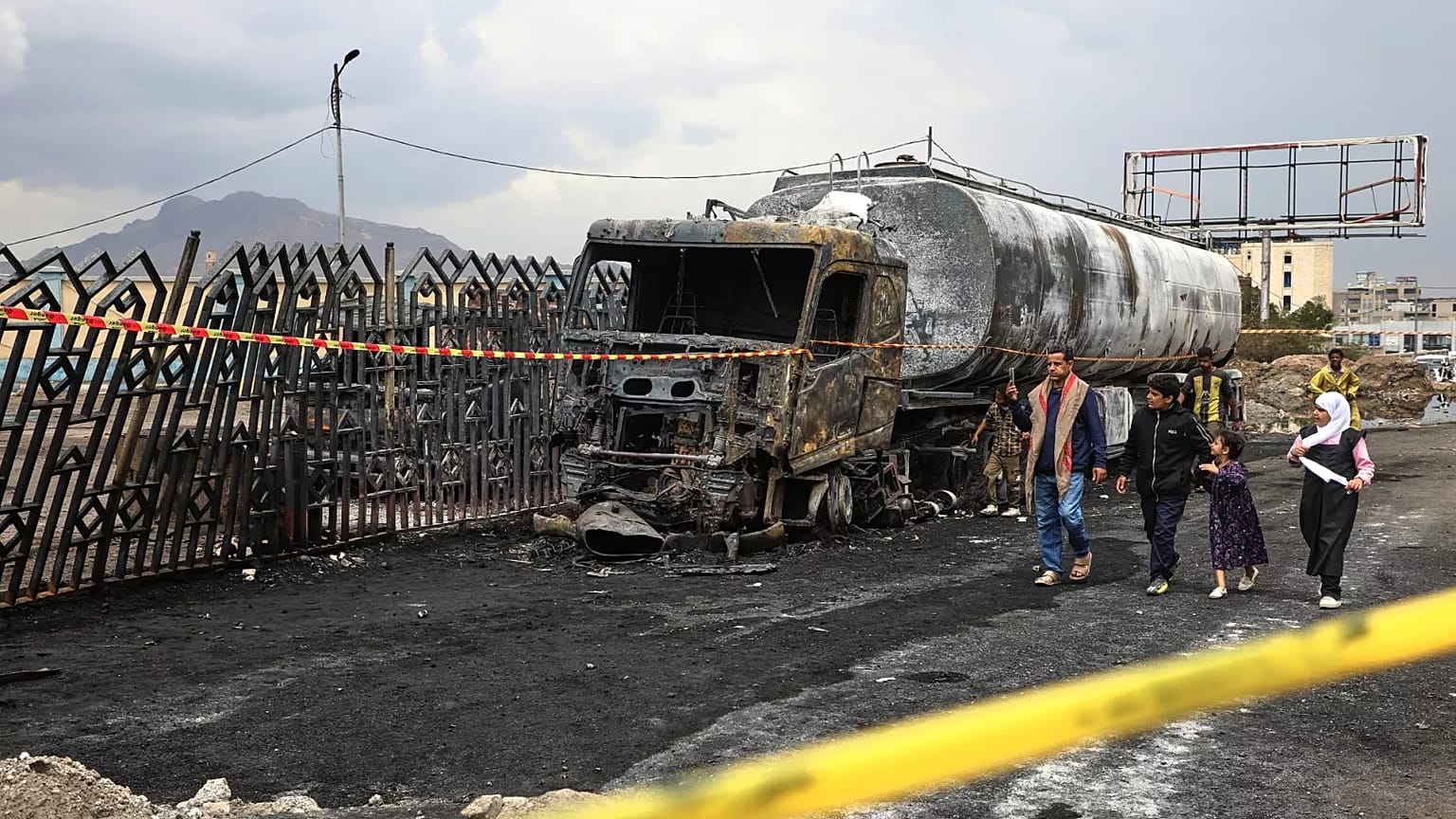 People walk past the wreckage of a fuel truck destroyed in Israeli airstrikes in Sanaa, 25 August, 2025