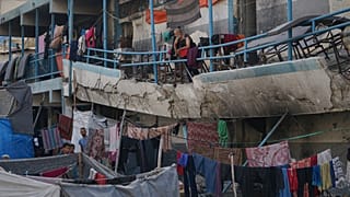 رجل فلسطيني نازح يقف على شرفة متضررة لمدرسة تُستخدم كمأوى في مدينة غزة، الأربعاء 27 آب/أغسطس 2025.