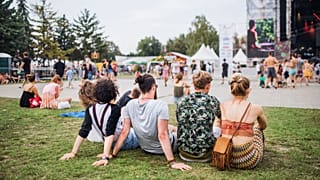 As pessoas sentam-se na relva num festival de música.
