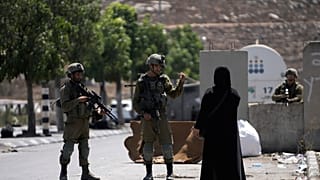  جنود إسرائيليون يتحدثون إلى امرأة فلسطينية قرب موقع هجوم دهس مزعوم قرب بيت هاجاي، وهي مستوطنة يهودية تقع على التلال جنوب مدينة الخليل الفلسطينية الكبيرة،