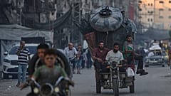 فلسطينيون نازحون فارون من شمال قطاع غزة يتنقلون مع أمتعتهم في أحد شوارع مدينة غزة، الجمعة 29 أغسطس/آب 2025. 