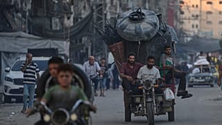  فلسطينيون نازحون فارون من شمال قطاع غزة يتنقلون مع أمتعتهم في أحد شوارع مدينة غزة، الجمعة 29 أغسطس/آب 2025. 
