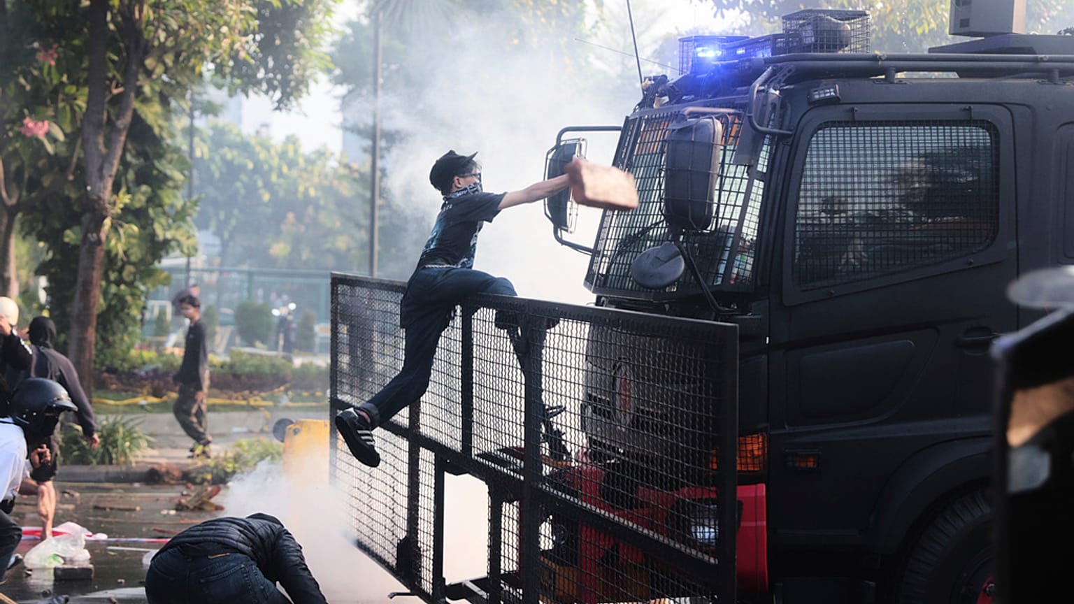 Um homem sobe para um camião de canhão de água da polícia durante um protesto na sequência da morte de um estafeta em confrontos entre a polícia de choque e estudantes