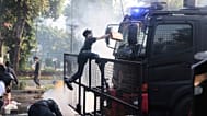 Un hombre sube a un camión de la policía con cañones de agua durante una protesta tras la muerte de un mensajero en los enfrentamientos entre la policía antidisturbios y los estudiantes.