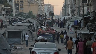 Displaced Palestinians fleeing northern Gaza Strip move with their belongings on a street in Gaza City, Friday, Aug. 29, 2025.