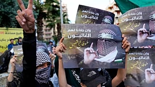 يظهر أحد المتظاهرين الفلسطينيين إشارة النصر، بينما يحمل آخرون صورًا لأبو عبيدة، المتحدث باسم كتائب القسام،بالقرب من السفارة المصرية في بيروت، لبنان، يوم السبت، 18 نوفمبر 2023.