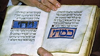 أحد أفراد المجتمع اليهودي في سراييفو يعرض كتاب الهاغاداه الذي يعود تاريخه إلى 700 عام في كنيس يهودي، السبت 15 أبريل/ نيسان 1995.
