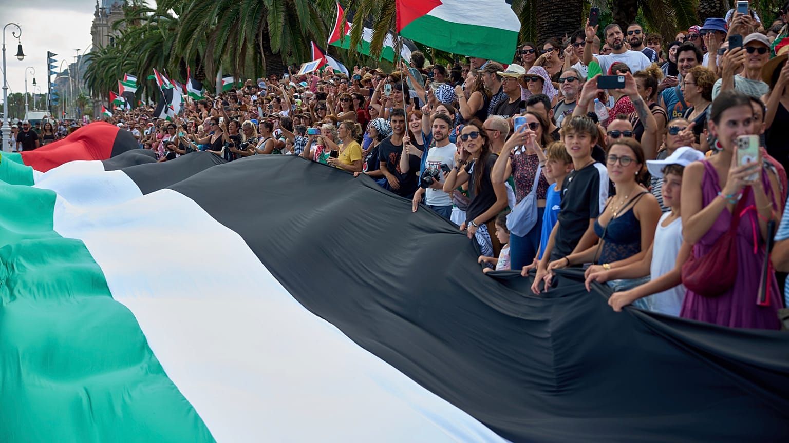 Personas ondean banderas palestinas mientras despiden a los activistas que zarpan en sus barcos para unirse a una flotilla civil con destino a Gaza, con el objetivo de romper 