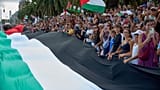 Personas ondean banderas palestinas mientras despiden a los activistas que zarpan en sus barcos para unirse a una flotilla civil con destino a Gaza, con el objetivo de romper 