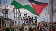 Activistas saludan desde un barco que participa en una flotilla civil con destino a Gaza en Barcelona, el 31 de agosto de 2025.