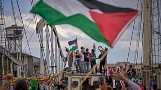 Activistas saludan desde un barco que participa en una flotilla civil con destino a Gaza en Barcelona, el 31 de agosto de 2025.
