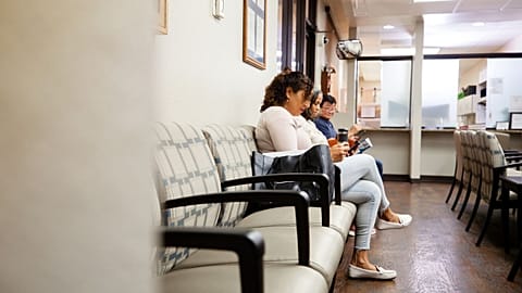 Patients sit in a doctor's office waiting room.