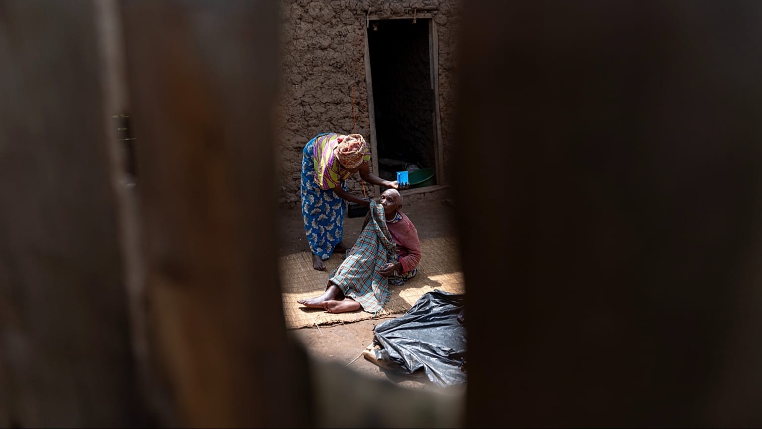 Una mujer limpia la cara de su madre, enferma de demencia, cerca de su casa en Kandago, un pueblo rural de Uganda, el 18 de noviembre de 2024.