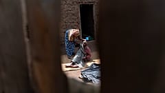 Bir kadın 18 Kasım 2024 tarihinde Uganda'nın kırsal bir köyü olan Kandago'daki evlerinin yakınında demans hastası annesinin yüzünü siliyor.
