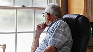 An older man looks out the window.