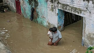 Ein Mann trägt seinen Sohn und watet durch Hochwasser, nachdem der Fluss Yamuna, der durch anhaltenden Regen in den höheren Regionen angeschwollen ist, über seine Ufer getreten ist, in Neu-Delhi, Indien, am 02.09.2025.