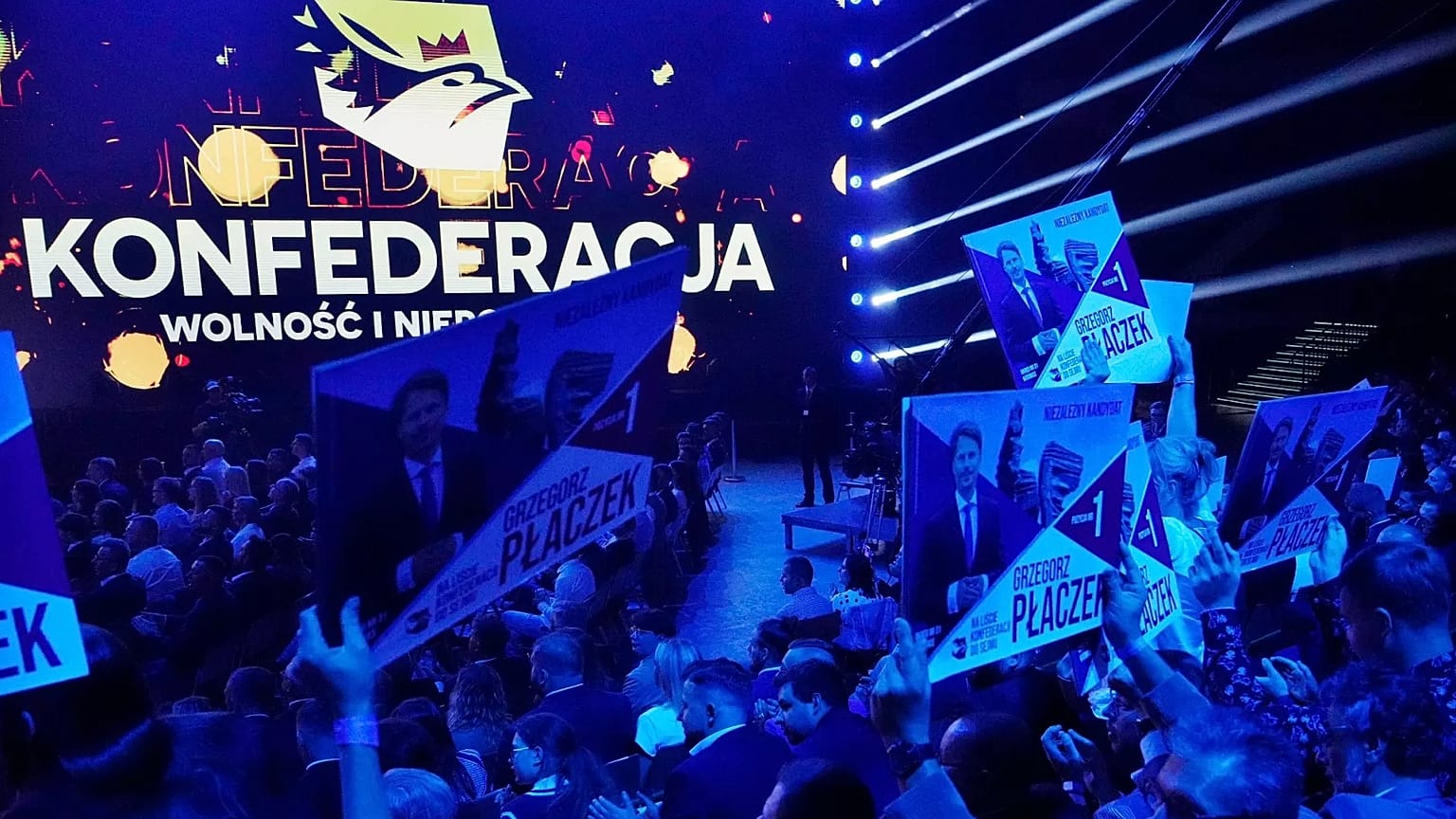 Supporters of the hard-right Polish party Confederation hold up a campaign poster in Katowice, 23 September, 2023