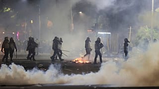 ضباط الشرطة يسيرون وسط دخان الغاز المسيل للدموع خلال احتجاج في سورابايا, جاوة الشرقية, إندونيسيا, يوم السبت, أغسطس. 30، 2025