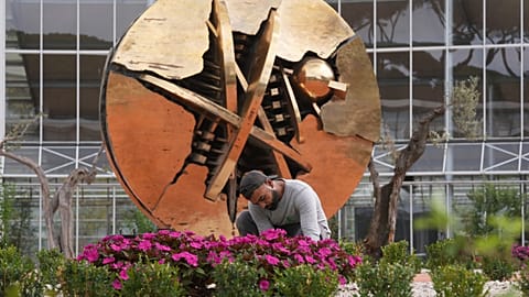 Singh Gurinder Pal, from India, tends to flowers in front of Arnaldo Pomodoro's sculpture 'The Rose of the Desert' in the plaza of the Laudato Si' Advance Training Centre.