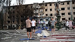DATEI: Bewohner stehen in der Nähe ihres zerstörten Hauses nach einem russischen Luftangriff in Saporischschja, 30. August 2025