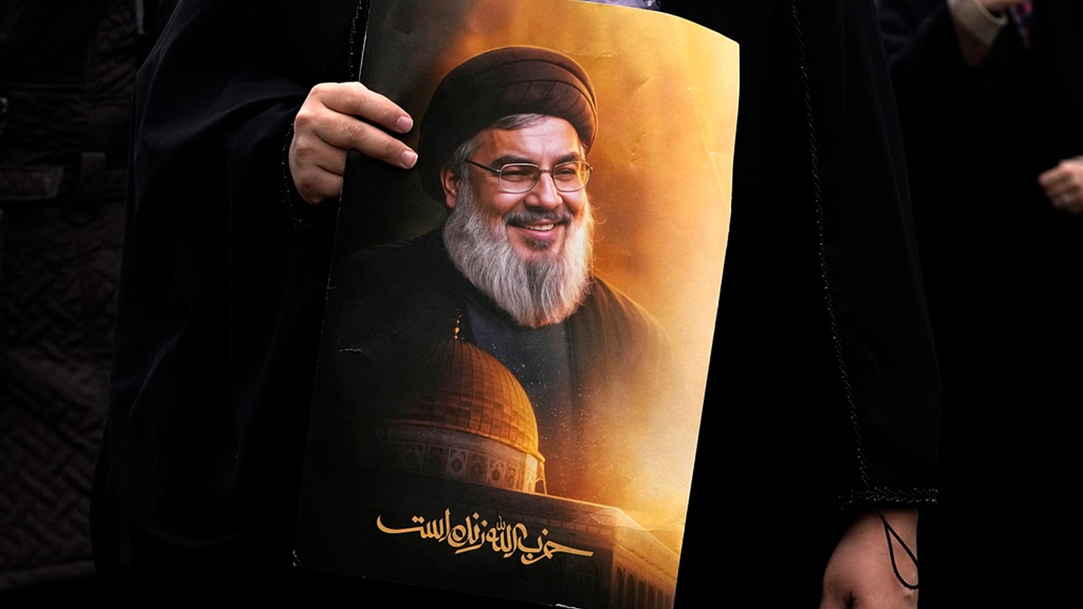 إيرانية تحمل لافتة تحمل صورة الأمين العام لحزب الله حسن نصر الله مكتوب عليها: "حزب الله حي"، خلال مسيرة يوم القدس السنوية
