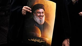 إيرانية تحمل لافتة تحمل صورة الأمين العام لحزب الله حسن نصر الله مكتوب عليها: "حزب الله حي"، خلال مسيرة يوم القدس السنوية