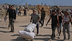 فلسطينيون ينقلون مساعدات قرب مركز توزيع تديره "مؤسسة غزة الإنسانية" وسط غزة، الإثنين 4 أغسطس 2025.