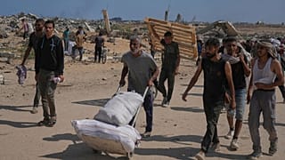 فلسطينيون ينقلون مساعدات قرب مركز توزيع تديره "مؤسسة غزة الإنسانية" وسط غزة، الإثنين 4 أغسطس 2025.