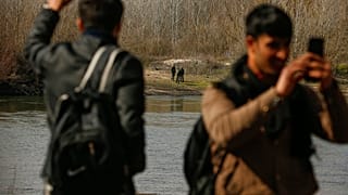  مهاجر يلوح للجنود اليونانيين أثناء محاولتهم دخول اليونان من تركيا عبر نهر ماريتسا قرب بوابة بازاركولي الحدودية في أدرنة، تركيا، الأحد 1 مارس/آذار 2020. 