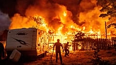 Anwohner versuchen, die Flammen eines brennenden Hauses in Tuolumne County, Kalifornien, am Dienstag, den 2. September 2025, daran zu hindern, auf ein Nachbarhaus überzugreifen.