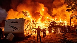 Residents work to stop flames from a burning home from spreading to a neighbouring house in Tuolumne County, Calif., on Tuesday, Sept. 2, 2025.