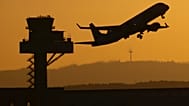 A passenger plane takes off from Frankfurt Airport in the last light of the day, flying past the tower of German Air Traffic Control (DFS), in Frankfurt/Main, Germany
